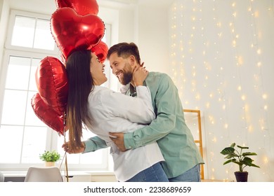 Happy, cheerful couple in love celebrating St Valentine's Day. Joyful, positive young man and woman enjoying Saint Valentine's Day, hugging, dancing with red heart shaped balloons, having fun together - Shutterstock ID 2238689659