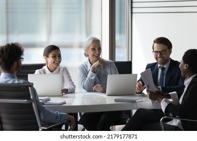 Happy Cheerful Diverse Different Aged Business Team Negotiating In Meeting Room, Brainstorming At Round Table, Talking, Discussing Reports, Startup Project, Laughing At Joke, Having Fun