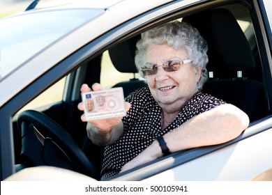 happy cheerful elderly senior woman driving her car and showing her drivers license