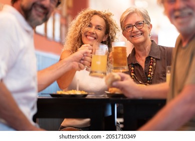 Happy cheerful family having fun and clinking beer glasses together while sitting at table in restaurant. Portrait of family toasting beer glasses and celebrating at restaurant