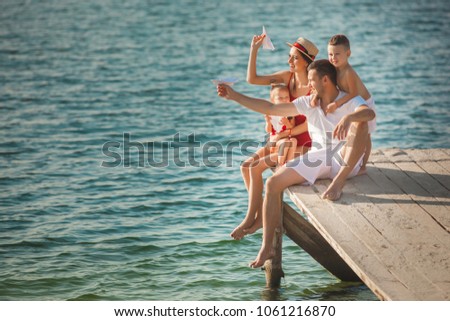 Happy cheerful family at the pier near the water having fun. Adorable kids playing with their parents