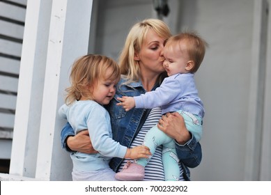 Happy cheerful family.Mother and her two baby kissing, laughing and hugging