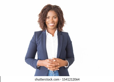 Happy Cheerful Female Consultant Looking At Camera. Young African American Business Woman With Clasped Hands Standing Isolated Over White Background, Smiling. Happy Entrepreneur Concept