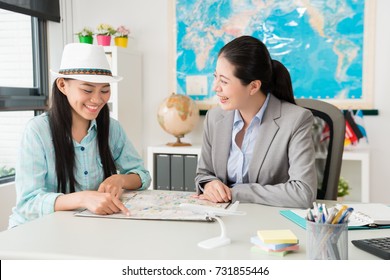 Happy Cheerful Female Traveler Pointing Map To Ask Trip Question And Discussing Best Itinerary Plan With Travel Agent Company Business Woman.