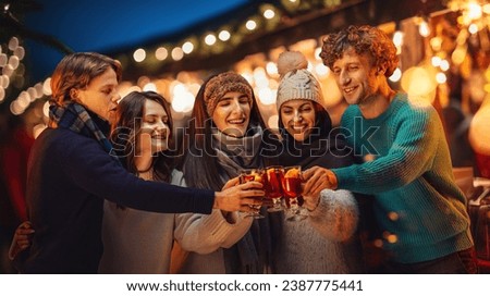 Happy, cheerful friends, men and women visiting outdoor fair in evening, celebrating, drinking mulled wine. Happy New Year. Concept of winter holidays, Christmas, traditions, outdoor fair, happiness