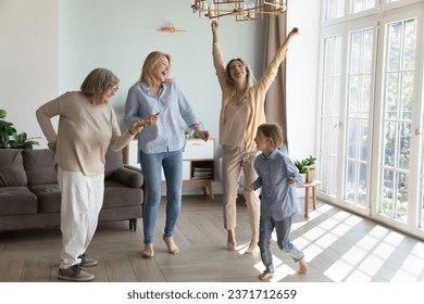 Happy cheerful girls and women of four female generations enjoying family party, energetic activity, dancing at home in living room, singing, laughing, celebrating mothers day - Powered by Shutterstock