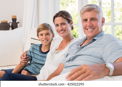 Happy And Cheerful Grandfather Sitting With His Daughter And Grandson. Portrait Of Multi Generation Family Looking At Camera.
