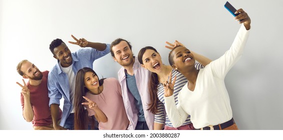 Happy Cheerful Laughing Young Adult Diverse College Student Friends Doing V Sign Hand Gesture Taking Group Phone Selfie Picture In Studio, Enjoying Best Time Of Life, Making Memories Together. Header