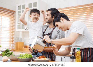 Happy cheerful LGBTQ couple cooking a food together in kitchen, a LGBT couple with adopted child cooking a food. Diversity lifestyles concept. - Powered by Shutterstock