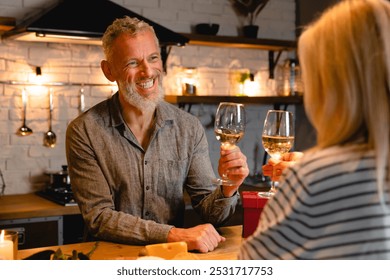 Happy cheerful mature couple celebrating anniversary or St. Valentines day on a date in the kitchen. Dining with wine alcoholic drink, togetherness at home - Powered by Shutterstock