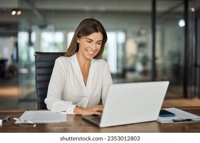 Happy cheerful mid aged business woman executive in office using laptop at work, smiling professional mature 40 years old female company manager working on computer at workplace. - Powered by Shutterstock