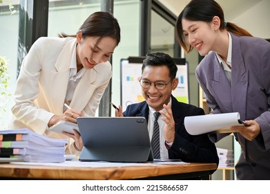 Happy and cheerful millennial Asian businesspeople are working on a project together, talking, sharing ideas, having a great time together in their office. - Shutterstock ID 2215866587