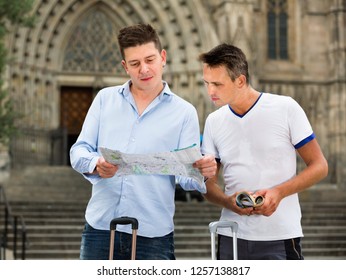 Happy cheerful positive male tourist couple looking at the map in the city - Powered by Shutterstock