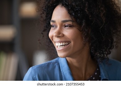 Happy Cheerful Pretty Black Girl Looking Away With Toothy Smile, Laughing. Beautiful Young Curly Haired Woman, Model, Dental Clinic Patient With White Teeth Posing Indoors. Candid Home Portrait