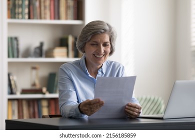 Happy cheerful retired mature business woman reading paper document, insurance agreement with good terms, conditions, sitting at laptop in office, smiling, feeling joy. Retirement, paperwork - Powered by Shutterstock