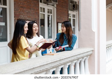 Happy, Cheerful, Stylish Female University Students Chat With Each Other About Books During Small Group Discussion In Corridor Of University, Hong Kong  