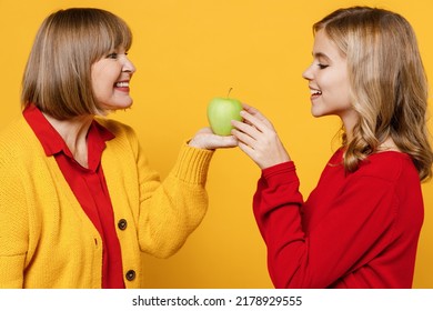 Happy cheerful vegetarian woman 50s in red shirt have fun with teenager girl 12-13 years old. Grandmother granddaughter hold green apple isolated on plain yellow background. Family lifestyle concept - Powered by Shutterstock