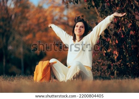 
Happy Cheerful Woman Enjoying Autumn Sitting in the Park.  Carefree lady de-stressing feeling healthy and optimistic
