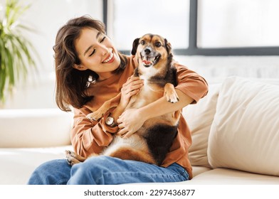 happy cheerful woman hugging her beloved pet dog at home on the couch - Powered by Shutterstock