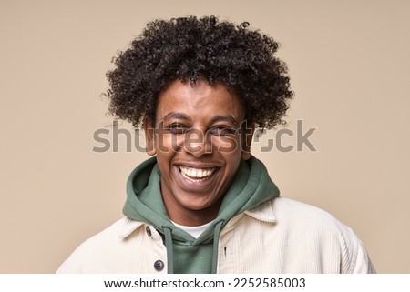 Happy cheerful young African American gen z guy isolated on beige background. Smiling funny ethnic teen student, cool curly generation z teenager laughing with white perfect teeth, close up portrait.