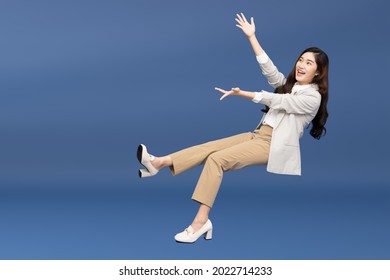 Happy cheerful young Asian businesswoman in suit floating in the air isolated on blue background, Presentation concept - Shutterstock ID 2022714233