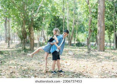 Happy cheerful young asian couple playing badminton game together in the park. urban asian sporty man and woman having fun outdoor sports and game activity concept. picnic and vacation. - Powered by Shutterstock