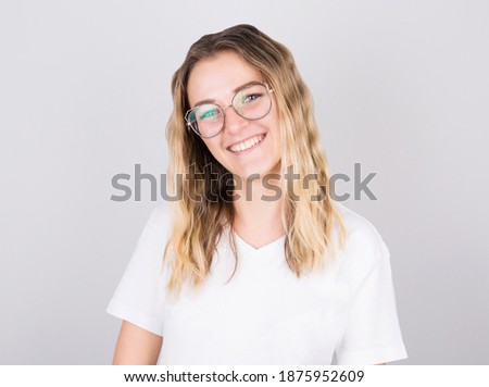 Happy cheerful young blonde girl looking at camera with joyful and charming smile.