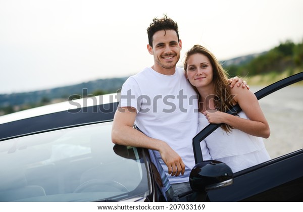 happy and cheerful young couple\
driving new car during holiday trip in summertime in\
countryside