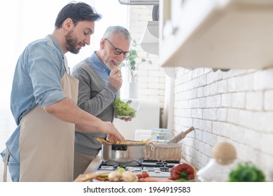 Happy cheerful young son helping his old senior father in preparing meal, food, dinner, lunch in the kitchen. Family time, cooking together. I love you, dad! Happy father`s day! - Powered by Shutterstock