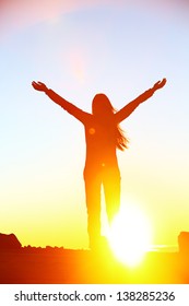 Happy cheering celebrating success woman at beautiful sunset above the clouds. Girl enjoying view of colorful sunset with arms raised up towards the sky. Happy free freedom concept image outdoors.