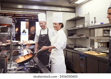 Happy, chefs and cooking with flame in professional kitchen for fine dining, hospitality and nutrition. Excited, people and catering with food for gourmet cuisine, dinner preparation in restaurant - Powered by Shutterstock