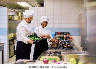 Happy chefs cooking together while working in the kitchen in a restaurant. Focus is on African American female chef. Copy space. 