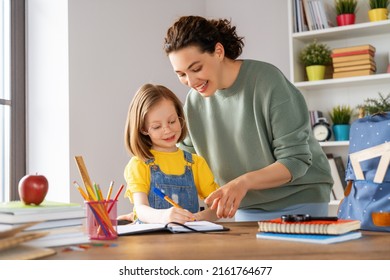 Happy Child And Adult Are Sitting At Desk. Girl Doing Homework Or Education.