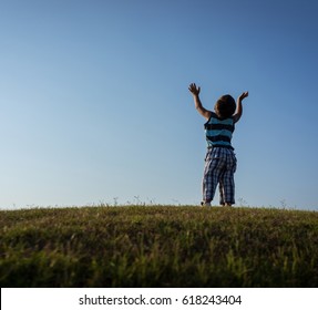 Happy Child With Arms Up With Beautiful Cloud And Grass Summer Meadow