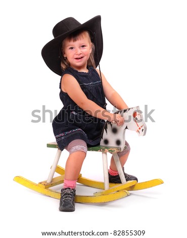 Happy child in big hat on a rocking horse.