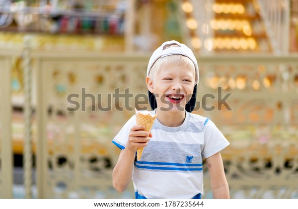 happy child boy 5-6 years old\
walking in an amusement Park and eating ice cream. Children\
lifestyle