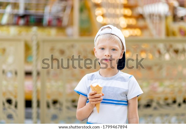 happy child boy 5-6 years old\
walking in an amusement Park and eating ice cream. Children\
lifestyle