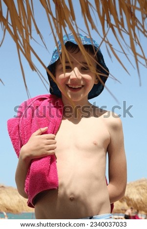 Happy child, happy boy, cute kid on beach after swimming in Doha city, Qatar. Summer swim. Bathing kid in water. Active sea recreation, rest. Summer swim, travel. Bathing child in water. Tourist child