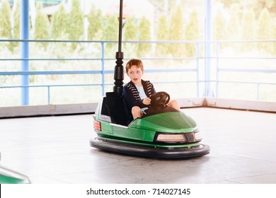 Happy child boy having fun in amusement park. Taking a ride on bumper car.