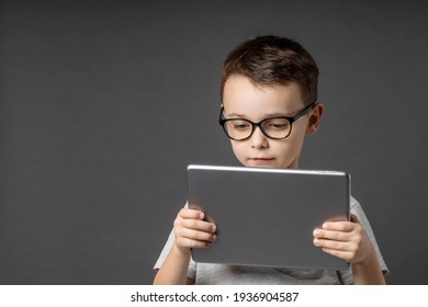 Happy child boy  holding a tablet ipade for your information on the blue background 
