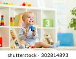 happy child boy holds elefant toy sitting on floor in nursery