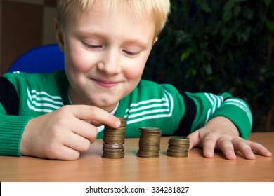 Happy Child (boy, Kid, Teen) Making Stacks Of Coins On The Table. Children And Money Concept.