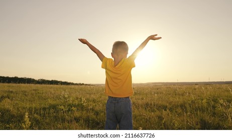 Happy Child Boy Prays, Spreading His Hands To The Sides At Sunset, Kid Praying To The Sun In Sky, Pulling Helping Hand, Enjoying Freedom Outdoors Walking In Nature In Park, Inspiring Childhood Dream