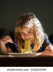 Happy Child Boy With Spoon Eats Itself. Cute Little Kid Eating Spaghetti Pasta At Home.