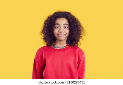 Happy Child In Casual Clothes. Positive Little Kid Isolated On Solid Bright Yellow Color Background. Studio Head Shot Of Pretty African American Girl In Red Sweatshirt Looking At Camera And Smiling