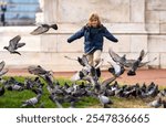 Happy child chasing birds, running on autumn day. Child run for pigeons. Running kids concept. Happy childhood. A Happy child chases running pigeons in park. Happy Child run with doves. Carefree Kid