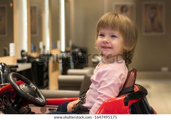 happy child in a\
children\'s hairdressing chair with a new haircut. hairdressing\
services for children