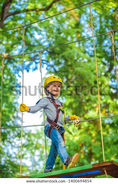 Happy child\
climbing in the trees. Balance beam and rope bridges. Roping park.\
Climber child on training. Rope park - climbing center. Child\
playing on the playground. Toddler\
age