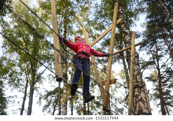 Happy child climbing in the trees. Rope park.
Adventure climbing. Rope
bridges.