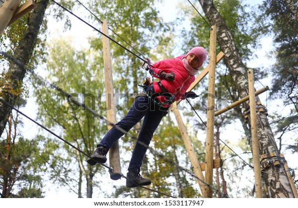 Happy child climbing in the trees. Rope park.\
Adventure climbing. Rope\
bridges.